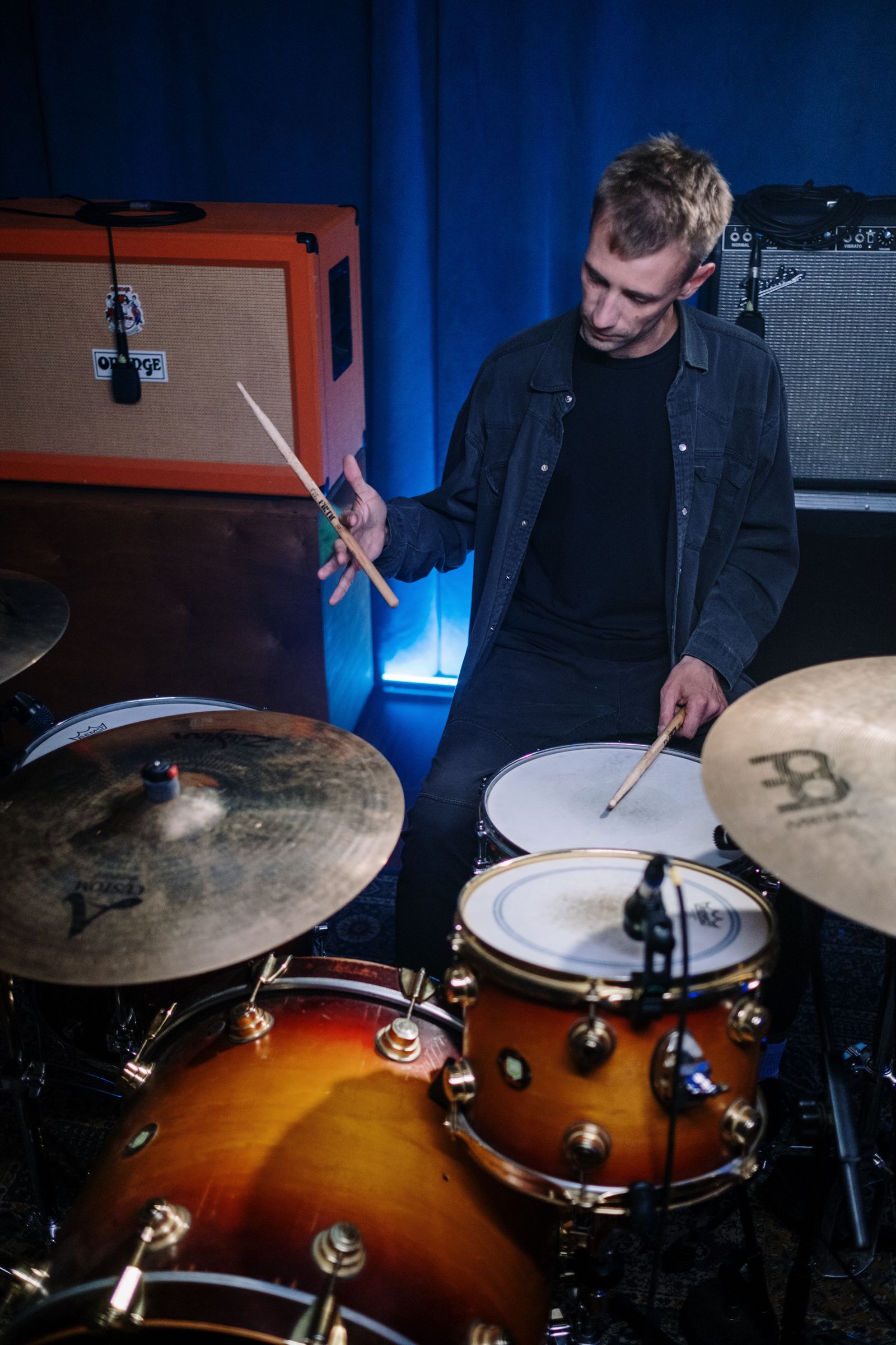 Adult drummer practicing on a drum kit during a studio lesson