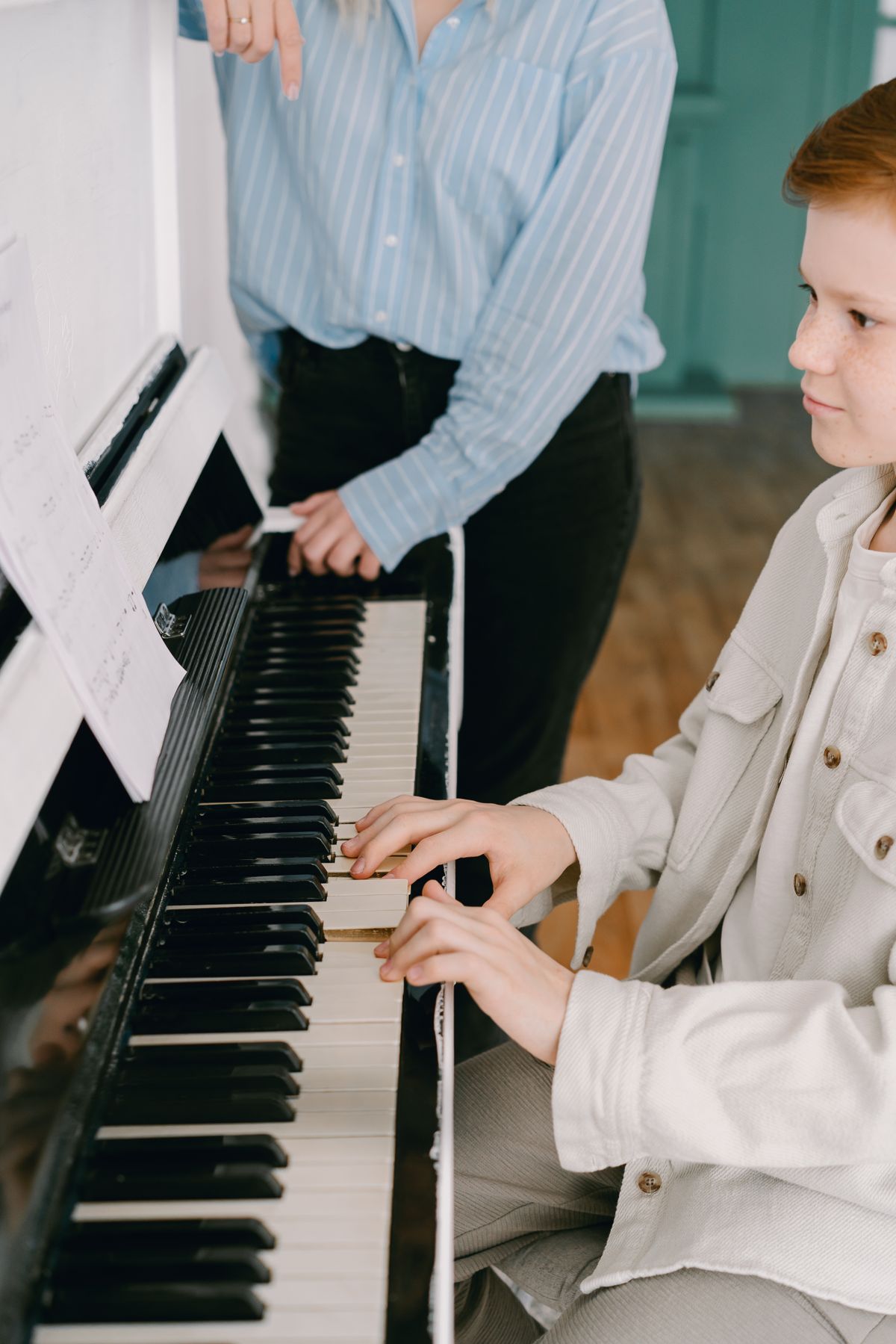 Instructor guiding a student during a private piano lesson