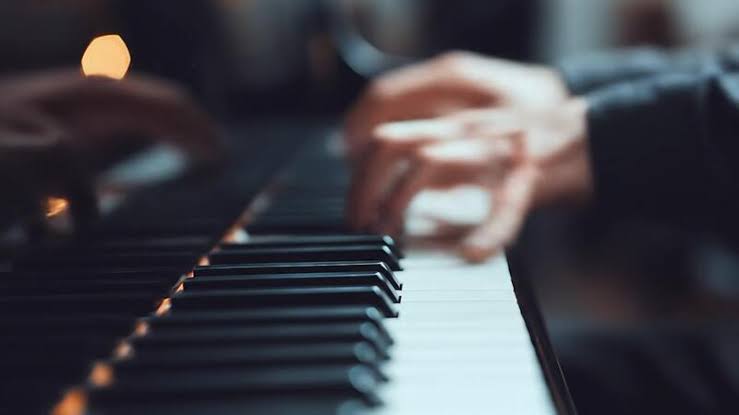 Hands playing piano keys in a warm, focused lesson setting